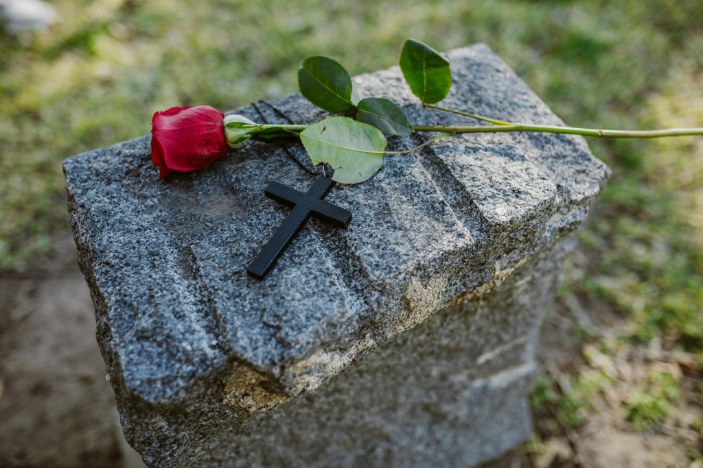 Rose and cross placed on stone memorial symbolizing loss after a serious accident