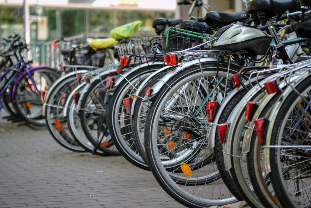 Row of parked bicycles lined up on an urban sidewalk near street traffic