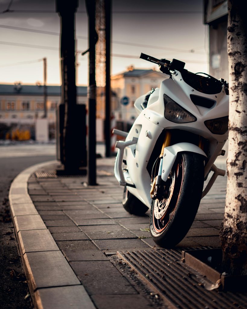 White motorcycle parked on a city street sidewalk near curbside before contacting motorcycle accidents attorney. 